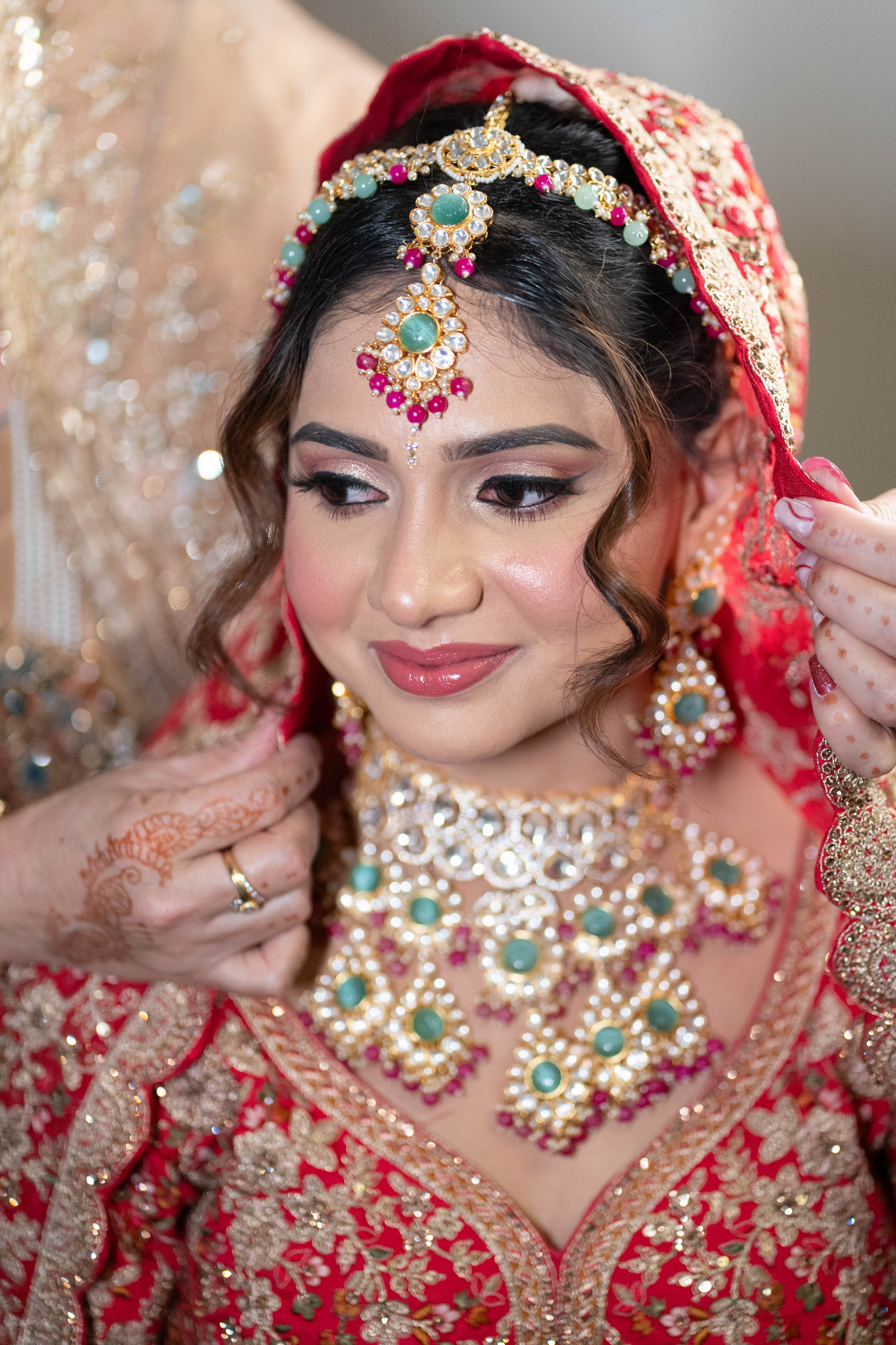 Bride with ornate gold and emerald jewelry during veil ceremony